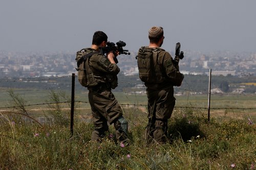Israeli soldiers stand on the Israeli side of the Israel-Gaza border