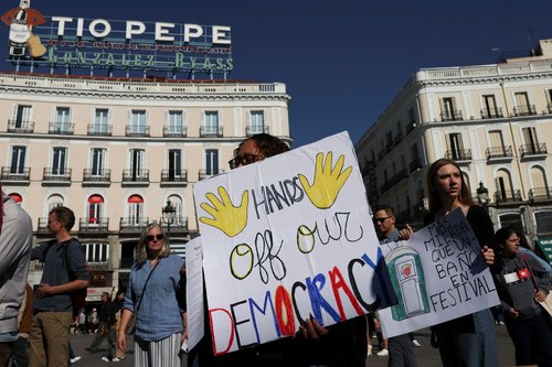 Demonstrators hold signs to protest against U.S. President Donald Trump and his administration during a 'No Kings' rally at Puerta del Sol in Madrid, Spain