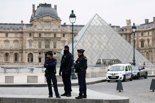 Police officers stand near the pyramid of the Louvre museum after reports of a robbery