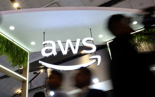 FILE PHOTO: People walk past the logo of Amazon Web Services (AWS)