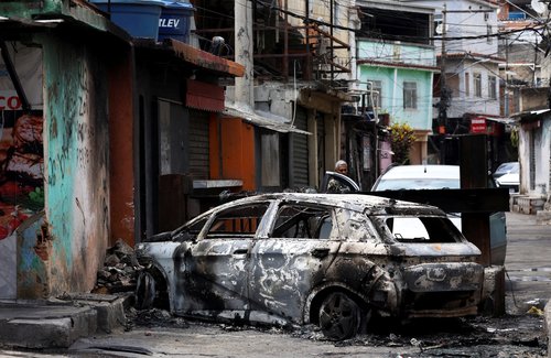 A person looks on behind a burnt car during a police operation against drug trafficking at the favela do Penha, in Rio de Janeiro, Brazil October 28, 2025. REUTERS/Aline Massuca TPX IMAGES OF THE DAY