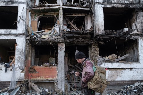 A man stands in front of a residential building that was recently hit by shelling in Kyiv