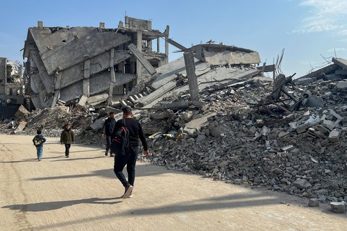 Palestinians walk past the rubble of destroyed houses, amid a ceasefire between Israel and Hamas, in Khan Younis in the southern Gaza Strip