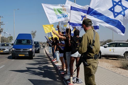 Mourners wave flags as a vehicle carries the body of Israeli hostage Yossi Sharabi, who, according to the Hostages Families Forum, was abducted alive and killed in captivity