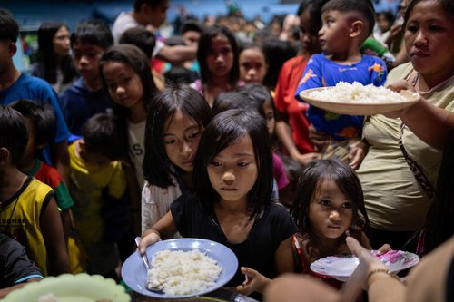 Residents who were evacuated ahead of Typhoon Fung-wong queue for food at an evacuation center in Cauayan