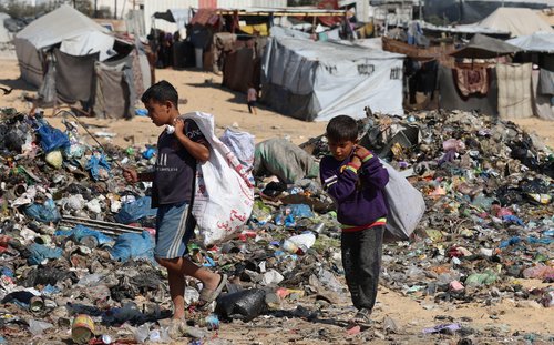 Palestinian children look through garbage near a landfill site in Khan Younis