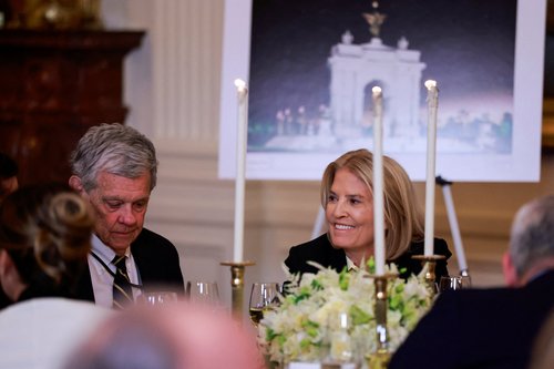 Greta Van Susteren and her husband John Coale sit in front of a rendering of an arch monument with a Lady Liberty statue on top during a ballroom dinner hosted by U.S. President Donald Trump