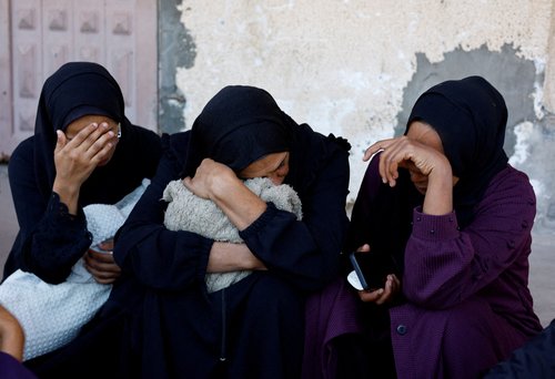 Mourners react as they attend the funeral of Palestinians who