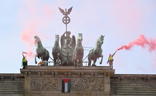 Pro-Palestinian protesters burn flares after attaching a flag of Palestine to the Brandenburg Gate