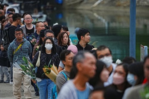 People queue to place flowers at a makeshift memorial near Wang Fuk Court housing estate to pay tribute to victims of the deadly fire at the Wang Fuk Court housing complex, in Tai Po, Hong Kong, China, November 30, 2025. REUTERS/Lam Yik
