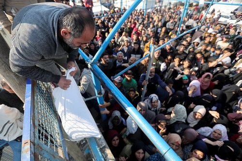 Palestinians receive flour bags distributed by UNRWA during a temporary truce between Hamas and Israel, in Khan Younis