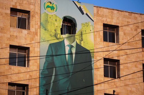 FILE PHOTO: A view shows a damaged poster of Syria's President Bashar al-Assad in Aleppo
