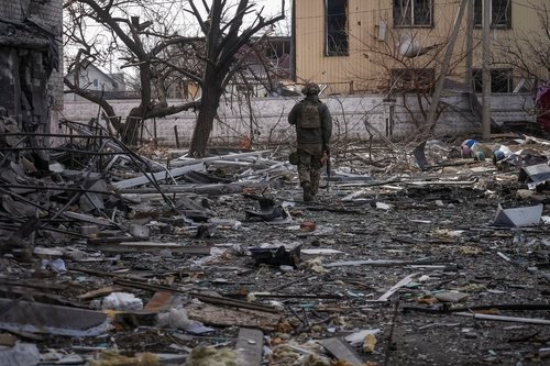 A Ukrainian serviceman passes by buildings damaged by Russian military strikes in the frontline town of Pokrovsk