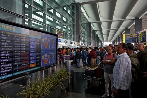 Travellers look at a flight schedule screen displaying several cancelled and delayed flights by IndiGo airlines at Kempegowda International Airport in Bengaluru, India, December 5, 2025. REUTERS/Priyanshu Singh
