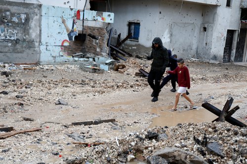 Palestinians walk during rainfall, after Israeli forces raided Jenin refugee camp in the Israeli-occupied West Bank