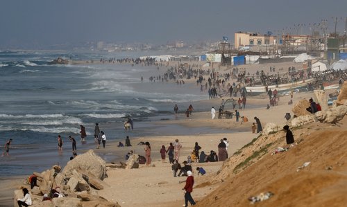 Palestinians gather on a beach in the hope of getting aid air-dropped, in the southern Gaza Strip