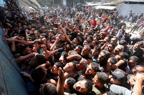 Palestinians gather to buy bread from a bakery, in Deir Al-Balah