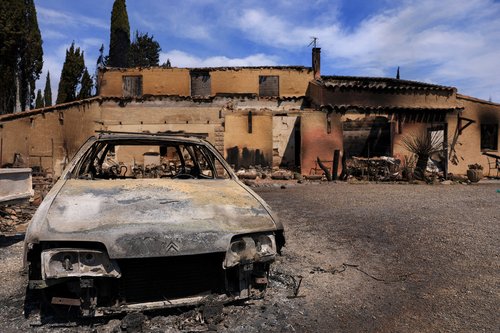 A destroyed car rests near a house damaged during a wildfire, in Saint-Laurent-de-la-Cabrerisse, near Narbonne southern France, August 6, 2025. REUTERS/Manon Cruz TPX IMAGES OF THE DAY