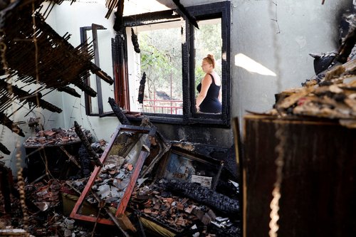 Dragana Vukovic passes by the window of her burned house, after a major wildfire swept through the area in the Piperi village near the capital Podgorica, Montenegro, August 12, 2025. REUTERS/Stevo Vasiljevic TPX IMAGES OF THE DAY