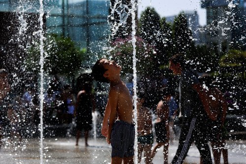 A kid plays in a fountain at the Andre Citroen park on a sunny and warm summer day
