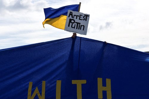 A pro-Ukraine supporter holds a placard and a Ukrainian flag during the "Alaska Stands with Ukraine" rally near Seward Highway in Anchorage, Alaska, U.S., August 14, 2025. REUTERS/Jeenah Moon REFILE - QUALITY REPEAT TPX IMAGES OF THE DAY