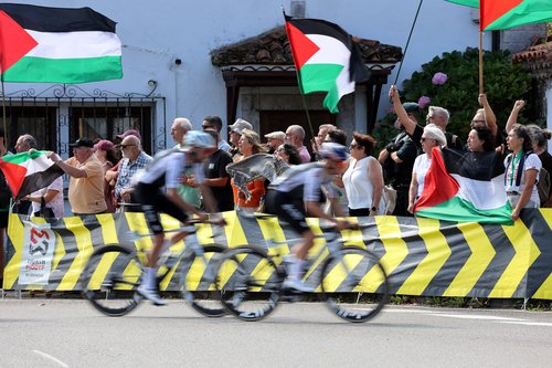 Cycling - Vuelta a Espana - Stage 13 - Cabezon de la Sal to L'angliru - Cantabria, Spain - September 5, 2025 Riders pass protesters with Palestine flags during stage 13 REUTERS/Pankra Nieto