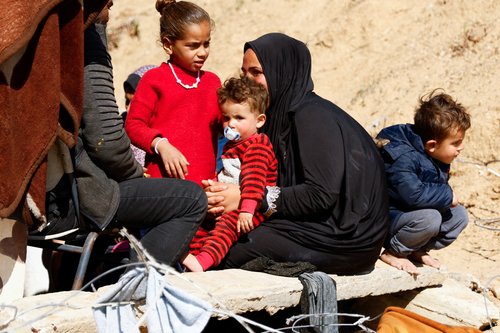 Displaced Palestinians sit outside their tent in Rafah