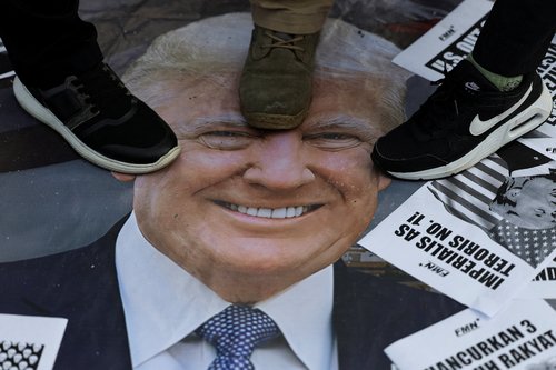 Activists step on a poster with the image of U.S. President Donald Trump
