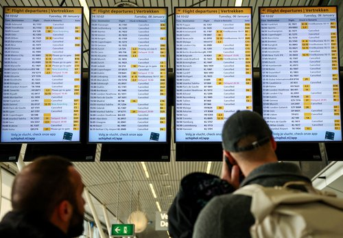 People look at departures screens showing delayed and cancelled flights at Amsterdam Airport Schiphol January 6, 2026. REUTERS/Piroschka van de Wouw