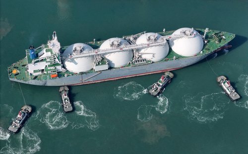 FILE PHOTO: A drone view shows tugboats assisting a liquified natural gas (LNG) tanker to dock at a port in Yantai