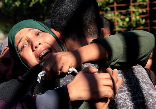 Mourners hug each other during the funeral of Palestinians