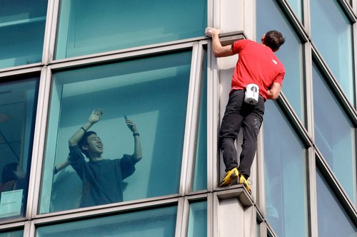 An onlooker waves at climber Alex Honnold free soloing Taipei 101 Skyscraper in Taipei, Taiwan, January 25, 2026 REUTERS/Ann Wang