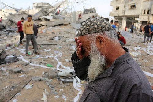 Palestinians inspect the site of an Israeli strike on a house belonging to Fojo family, in Rafah