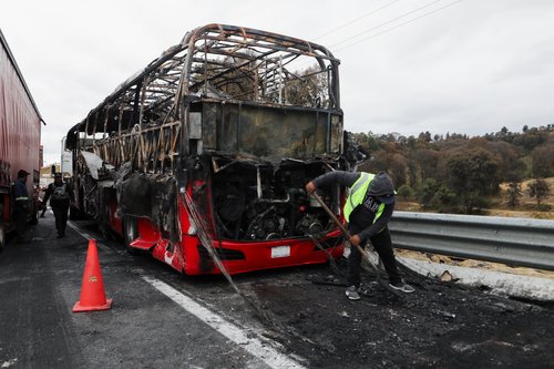 A burnt bus stands at the site on the highway connecting Mexico City with the state of Puebla, following roadblocks and arson attacks carried out by members of organized crime in several states after a military operation in which a government source said