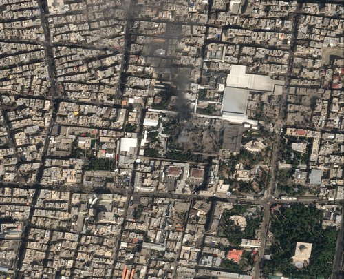 A satellite image shows black smoke rising and heavy damage at Iranian