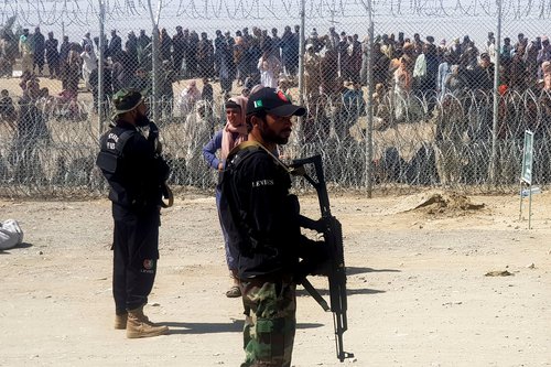 Pakistan's paramilitary soldiers stand guard in front of people who gather and wait to cross at the Friendship Gate crossing point in the Pakistan-Afghanistan border town of Chaman