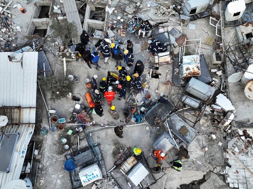 Rescuers try to free a child trapped under the rubble, following the deadly earthquake in Hatay