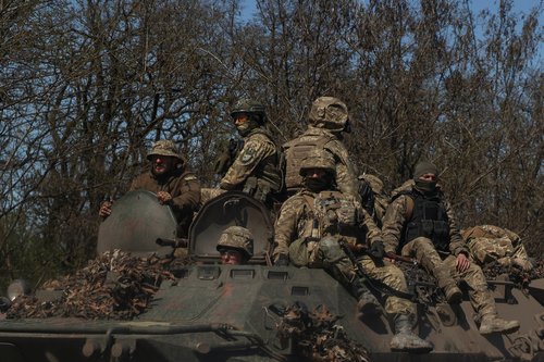 Ukrainian service members ride atop of an armoured personnel carrier near a front line in Donetsk region