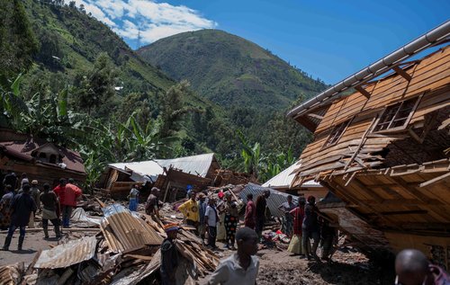 Congolese civilians gather after the death of their family members following rains that destroyed buildings and forced aid workers to gather mud-clad corpses into piles in the village of Nyamukubi