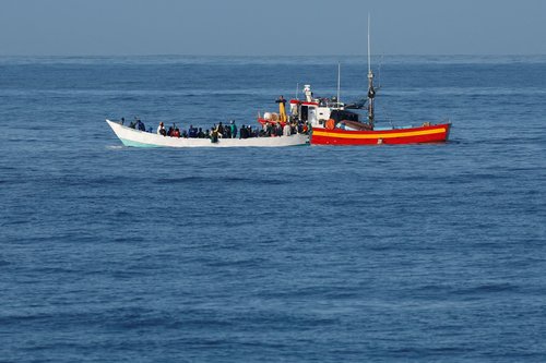 FILE PHOTO: Fishing boat helps a wooden boat with migrants, near the coast on the Bahia Feliz Beach