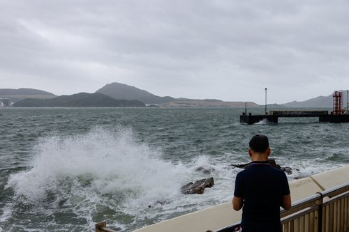 A man watches the waves at the seaside as Typhoon Talim approaches, in Hong Kong