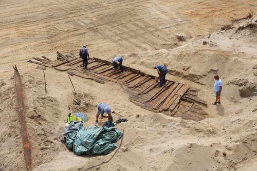 Archaeologists excavate the hull of a wooden ship, an ancient Roman flat-hulled riverine vessel