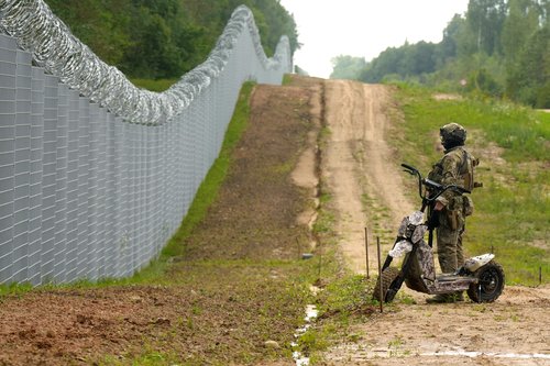 Latvian special unit Border Guard officer patrols along the fence at Latvian-Belarus border near Robeznieki