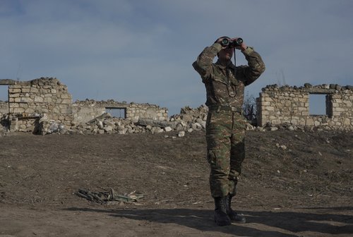 FILE PHOTO: An ethnic Armenian soldier looks through binoculars as he stands at fighting positions near divided Taghavard village in Nagorno-Karabakh region