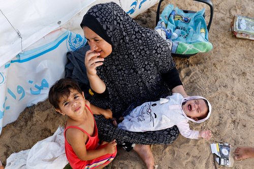 Displaced Palestinians, who fled their houses amid Israeli strikes, take shelter at a United Nations-run centre, in Khan Younis