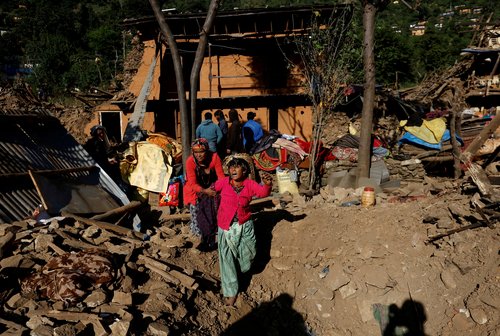 FILE PHOTO: Woman cries as she stands on the rubble of her collapsed house where the members of her family died during an earthquake in Jajarkot