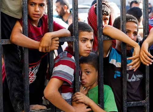 Children wait for the arrival of Palestinian workers, who were in Israel during the Hamas October 7 attack, at the Rafah border after being sent back by Israel to the strip, in the southern Gaza Strip