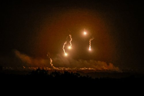 Flares burn in the sky as seen from the Israeli side of the border with Gaza
