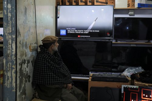 A man watches a news channel on television inside a shop after the Pakistani foreign ministry said the country conducted strikes inside Iran targeting separatist militants, in Peshawar