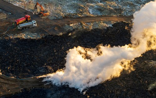 FILE PHOTO: A construction vehicle is seen near a steaming lava flow following a volcanic eruption on the edge of the town of Grindavik, Iceland